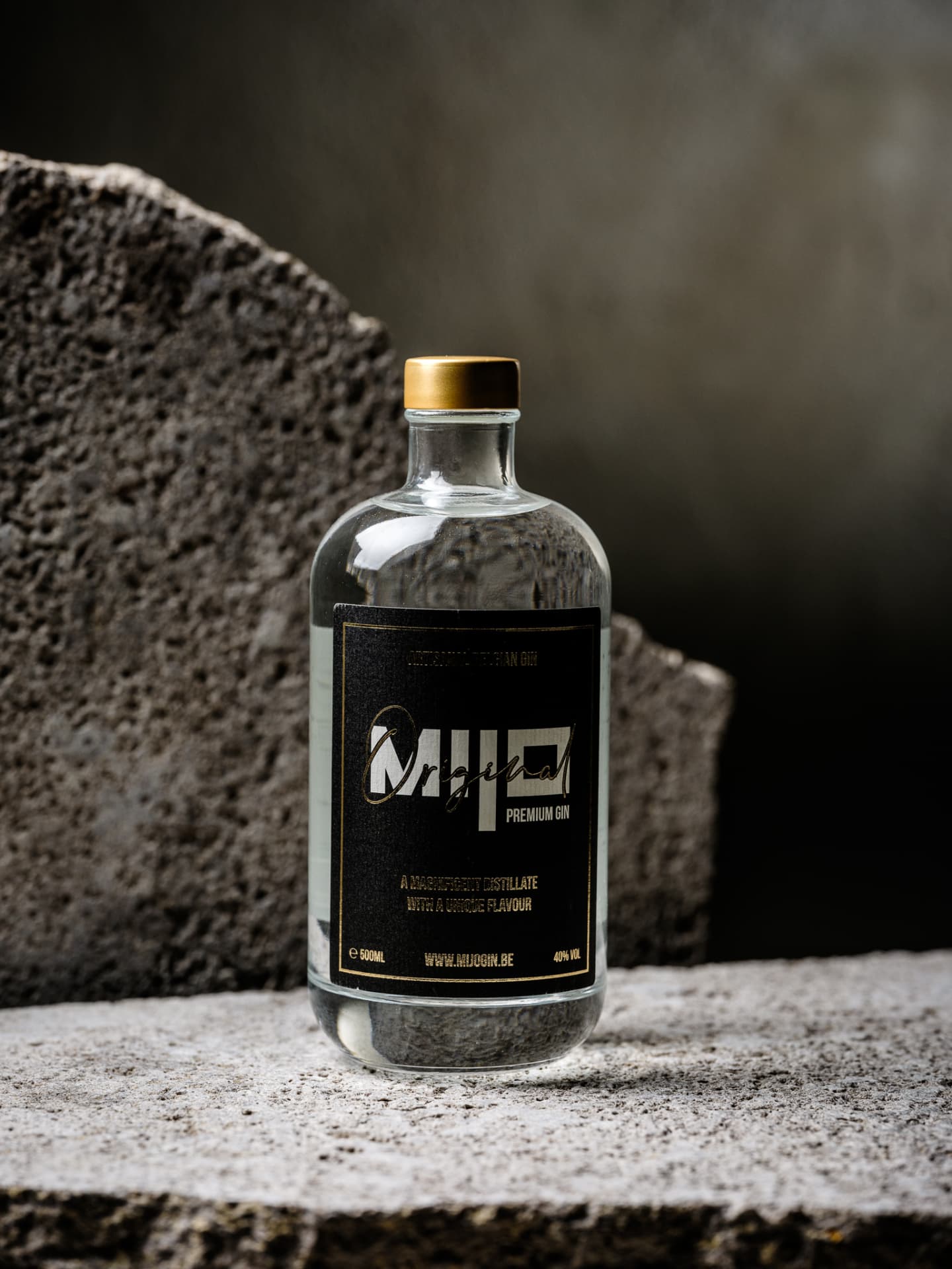 Close-up van de Mijo Gin-fles en het zwarte etiket op een stenen oppervlak