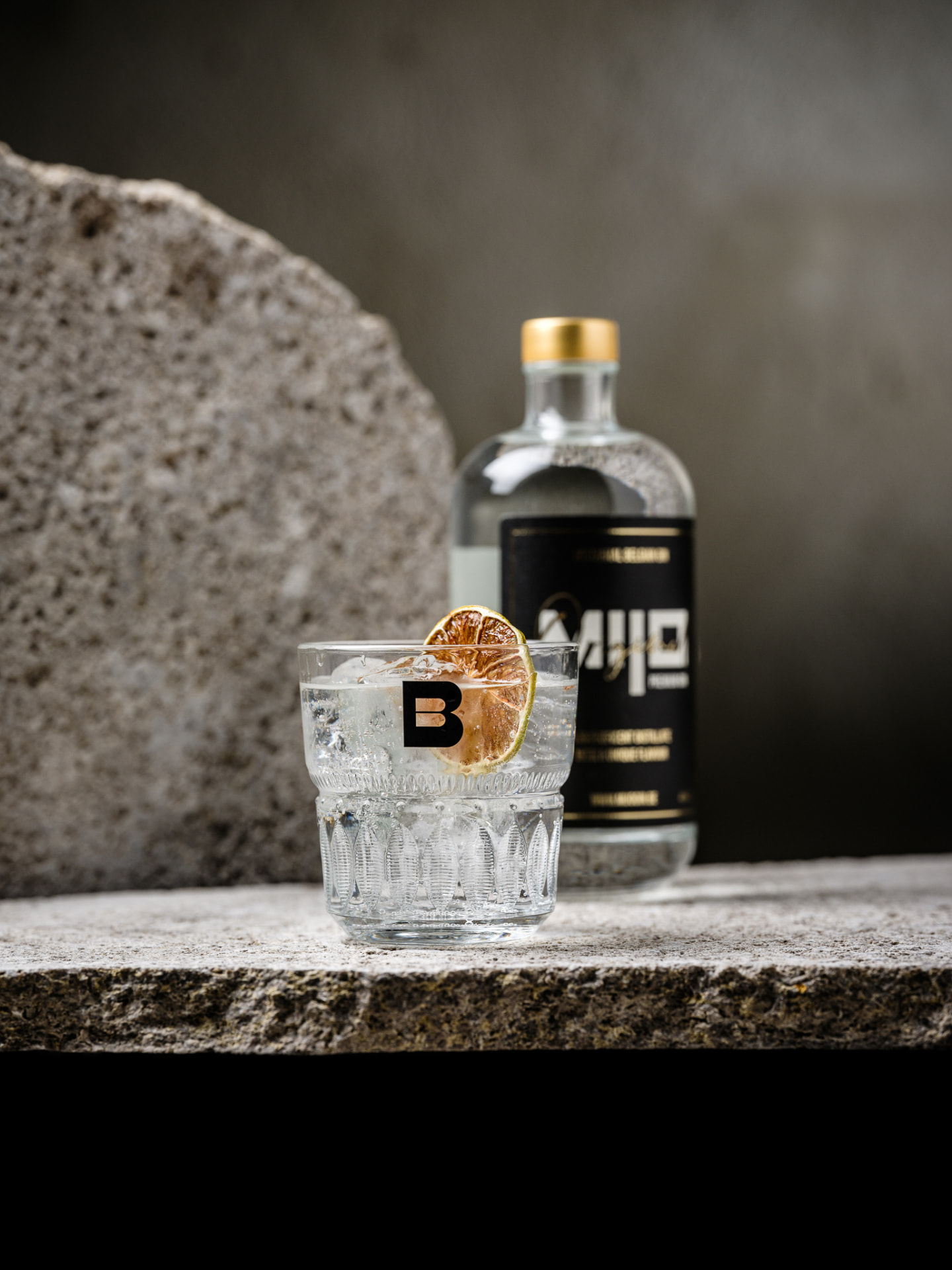 Een afgewerkte Mijo Gin serve naast de fles in warm, sfeervol licht